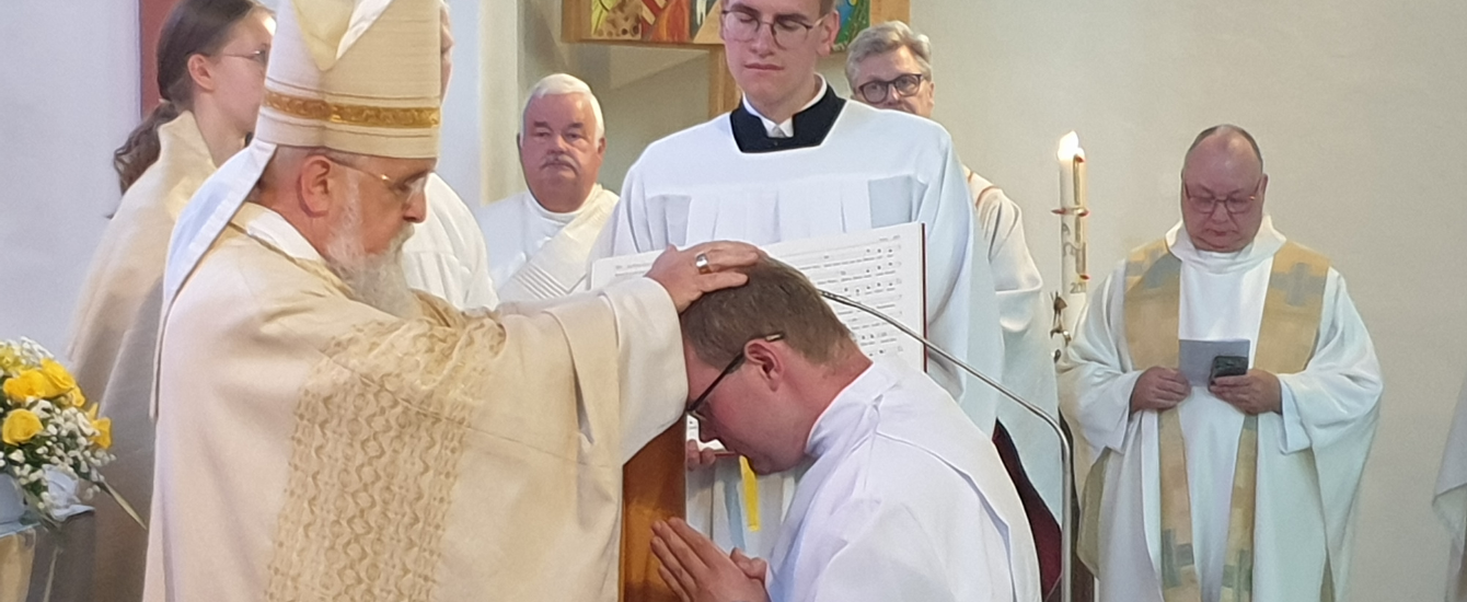 Ein Bischof segnet einen Diakon, der vor ihm kniet