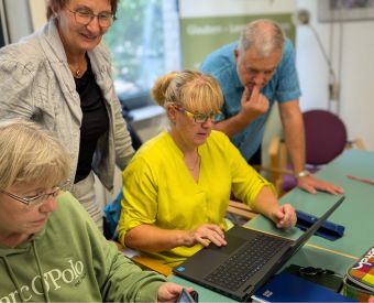 Menschen stehen und sitzen vor Laptops